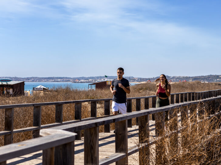 Casal a correr nos passadiços à beira-mar no Alvor
